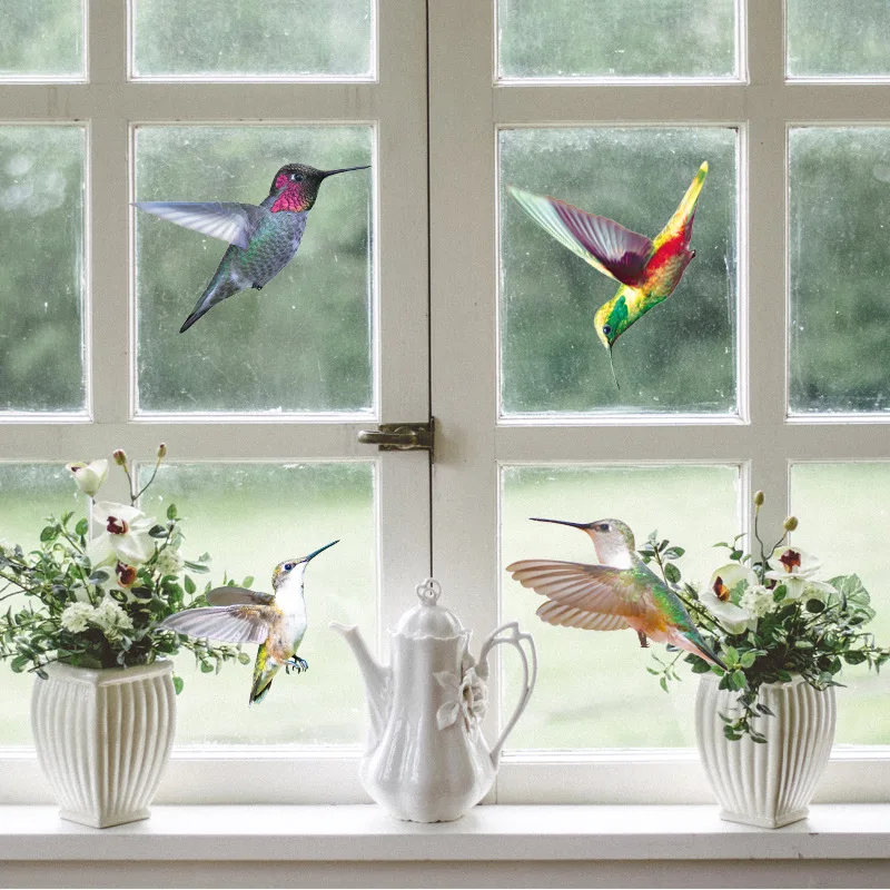 Hummingbird window decals on a white-framed window above a sill with flowers