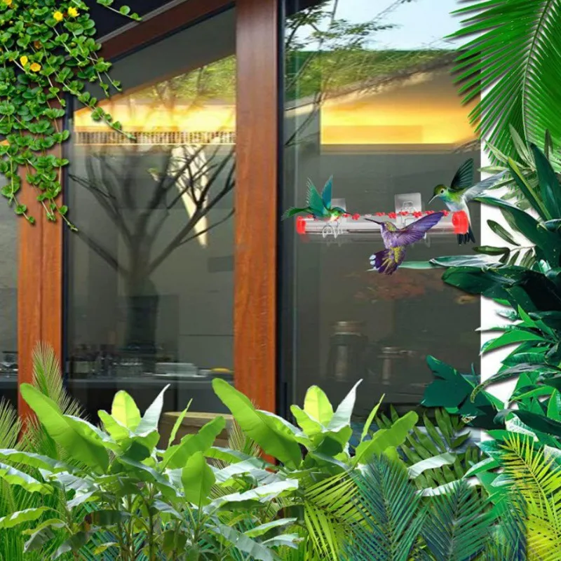 Hummingbird feeding at a tube feeder on a glass door