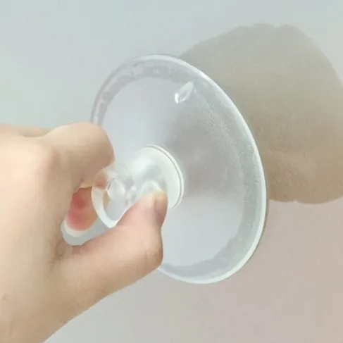 Hand pressing a clear 45 mm suction cup onto glass